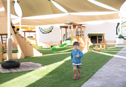 A young boy standing in front of a play area.