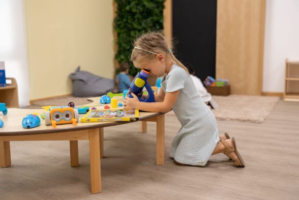A little girl playing with toys in a playroom.