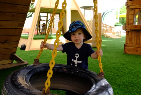 A young boy swinging on a tire swing.