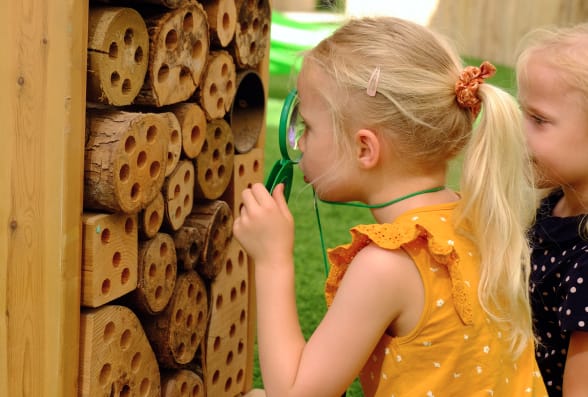 Two little girls looking at a wooden beehive.